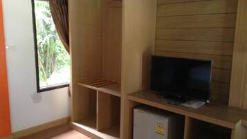 Een kamer met een houten garderobe, een televisie en een kleine koelkast.