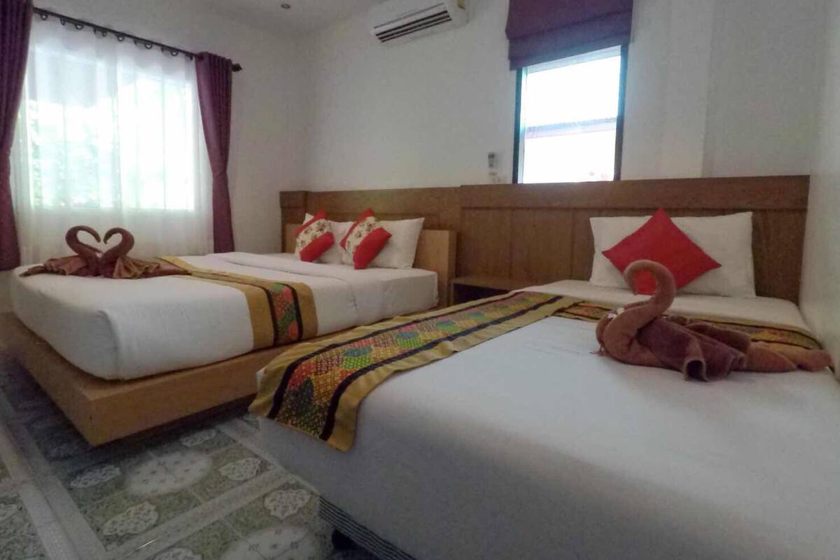 A hotel room with two beds, a wooden headboard, a patterned rug, and a window with curtains.
