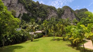 A lush garden with a view of a mountainous cliff. - Vipa Tropical Resort (Krabi)
