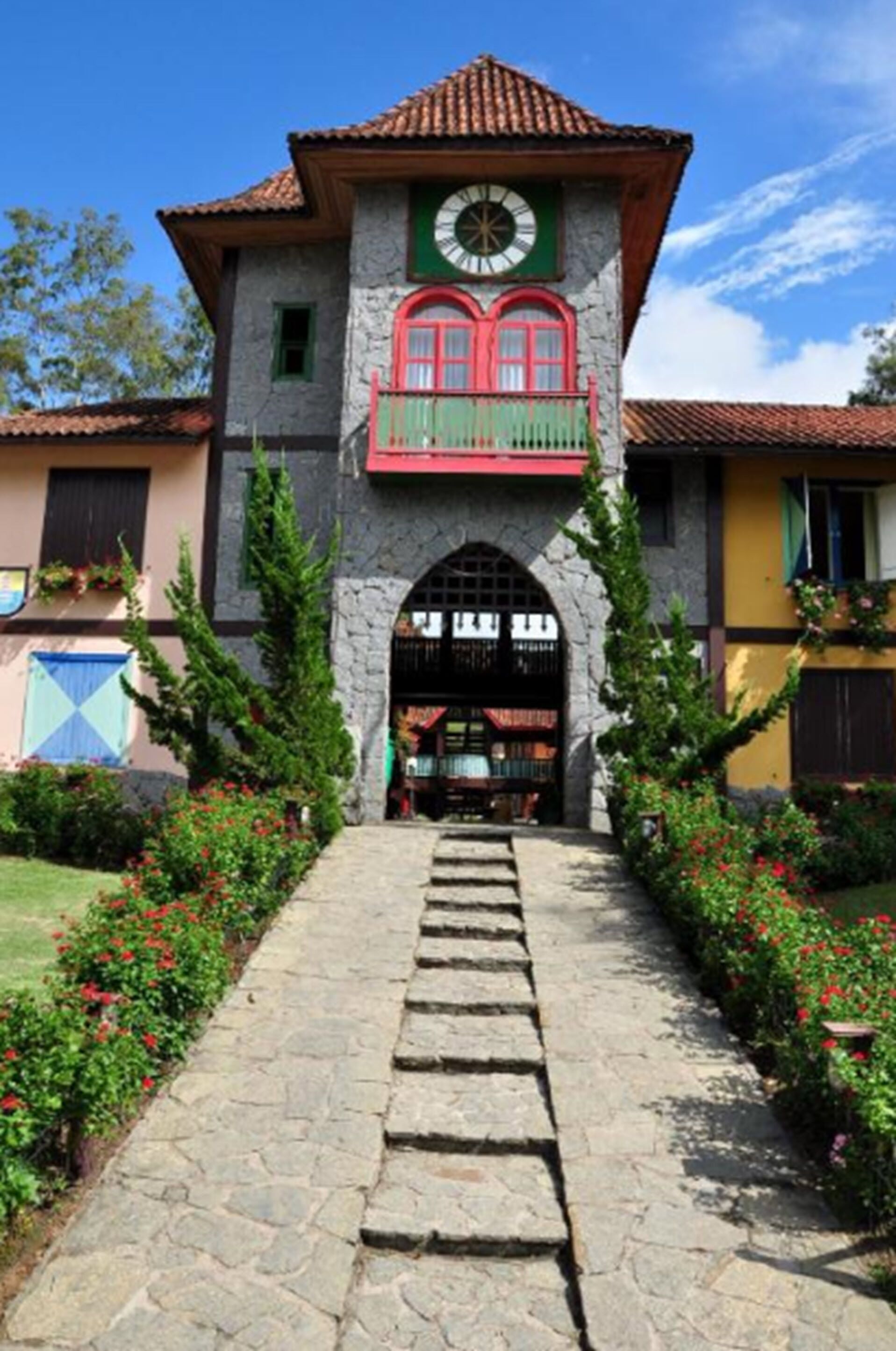 A building with a stone facade, a clock on the upper level, and a red balcony.