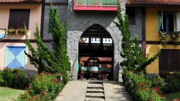A building with a stone facade, a clock on the upper level, and a red balcony.