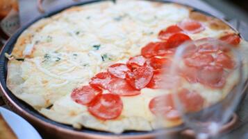 A pizza with pepperoni on a copper pan on a wooden table.