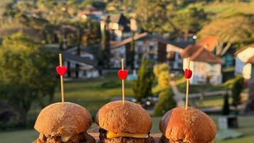 Trois hamburgers présentés sur une planche en bois, avec une chaîne de montagnes en arrière-plan.