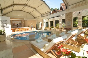 Una piscina al aire libre, sombrillas, sillones reclinables de piscina