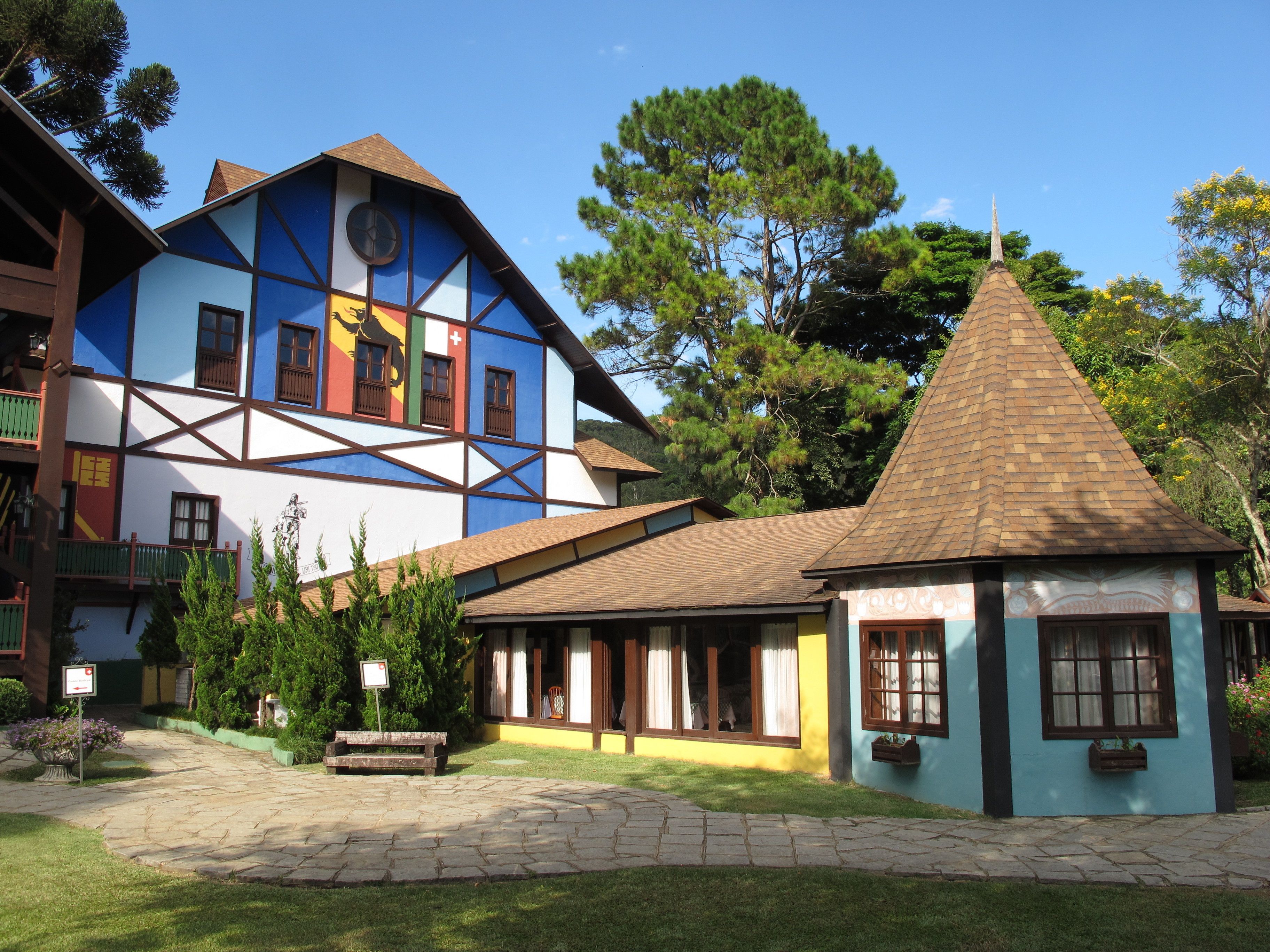 A traditional half-timbered building with a small adjacent structure, surrounded by well-maintained gardens and trees.