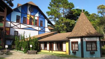 A traditional half-timbered building with a small adjacent structure, surrounded by well-maintained gardens and trees.