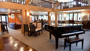 A spacious room with a grand piano, wooden furniture, and a balcony with a railing. - Hotel Village Le Canton (Teresópolis)