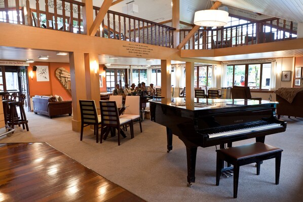 A spacious room with a grand piano, wooden furniture, and a balcony with a railing.
