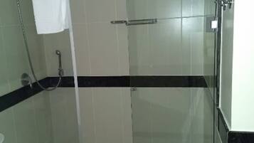 A glass-enclosed shower area with a white towel hanging on a rack, a glass door, and a tiled floor.