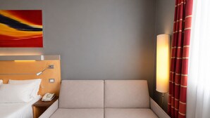 Habitación de hotel con cama, mesita de noche, lámpara y un cuadro en la pared.