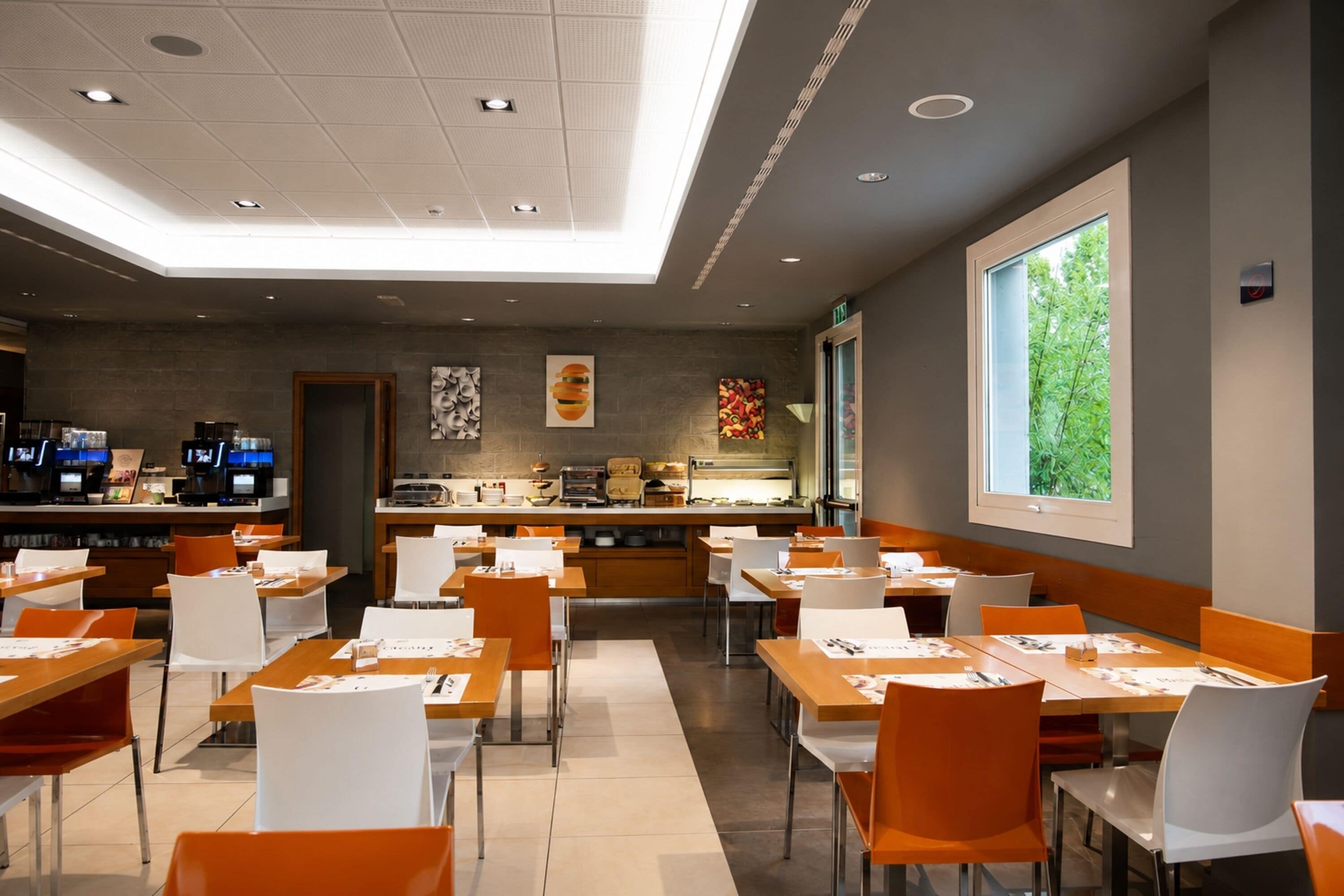Un interior de restaurante moderno con una barra larga, varias mesas y sillas.