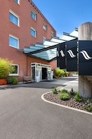 L'ingresso di un hotel con una tettoia in vetro, una panchina e un vialetto che conduce all'ingresso.