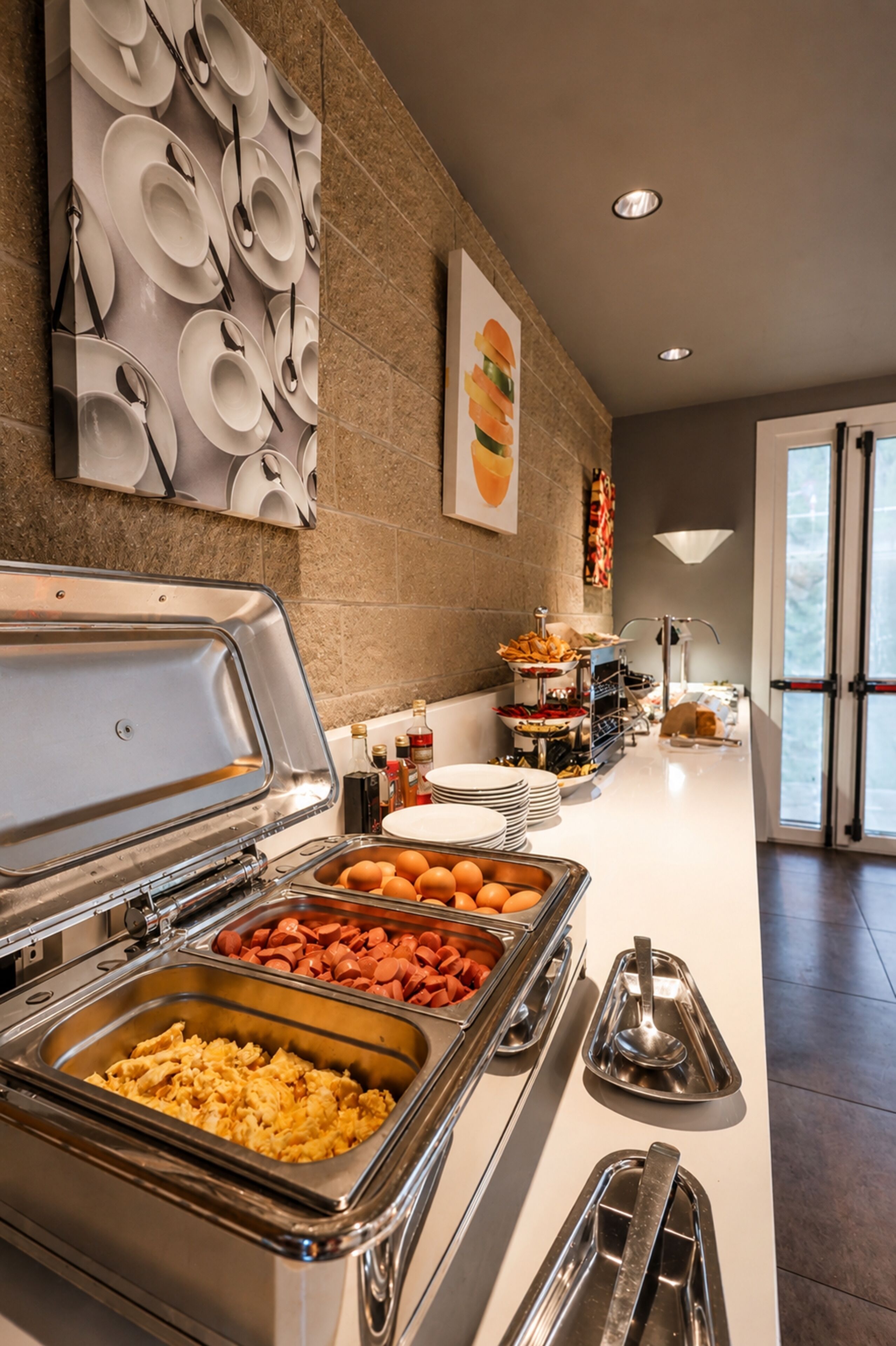 Ein reichhaltiges Buffet mit verschiedenen Speisen, einem an der Wand befestigten Tellerregal und einer Tür, die nach draußen führt.