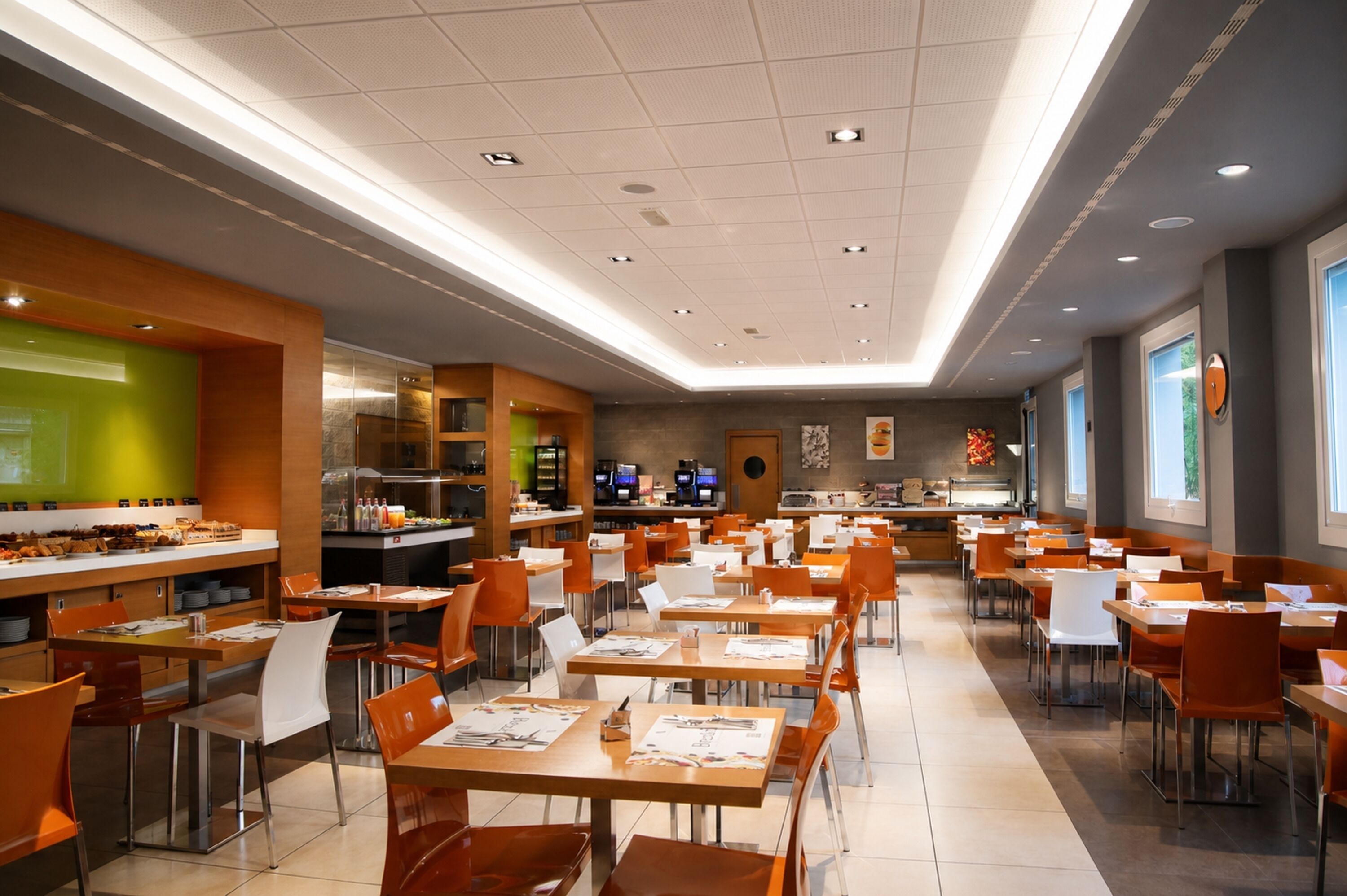 Uma cafeteria ampla com várias mesas e cadeiras, uma área de buffet e uma cozinha ao fundo.