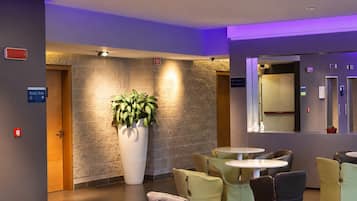 A lobby with a curved seating area, a large potted plant, a reception desk, and a wall-mounted mirror.