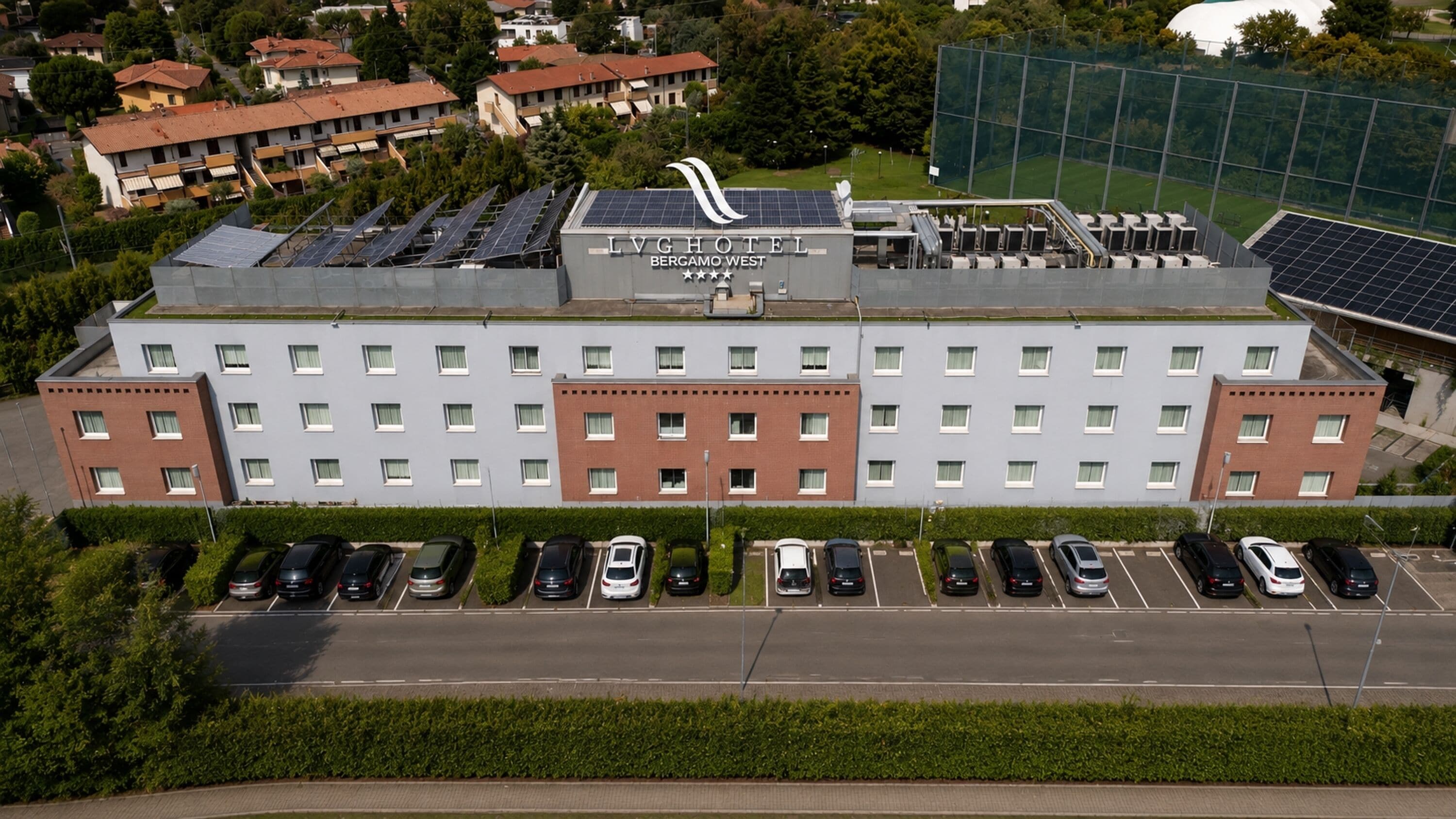 Un hotel con techo solar, varios espacios de estacionamiento y vistas de edificios circundantes.