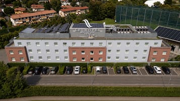 Un hotel con techo solar, varios espacios de estacionamiento y vistas de edificios circundantes.