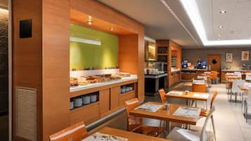 Un café moderne avec des éléments décoratifs en bois, un bar où l’on peut prendre le petit-déjeuner et des places assises pour les clients.