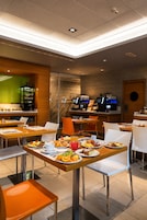 Un restaurante moderno con varias mesas y sillas, una zona de bar y una barra con menú.