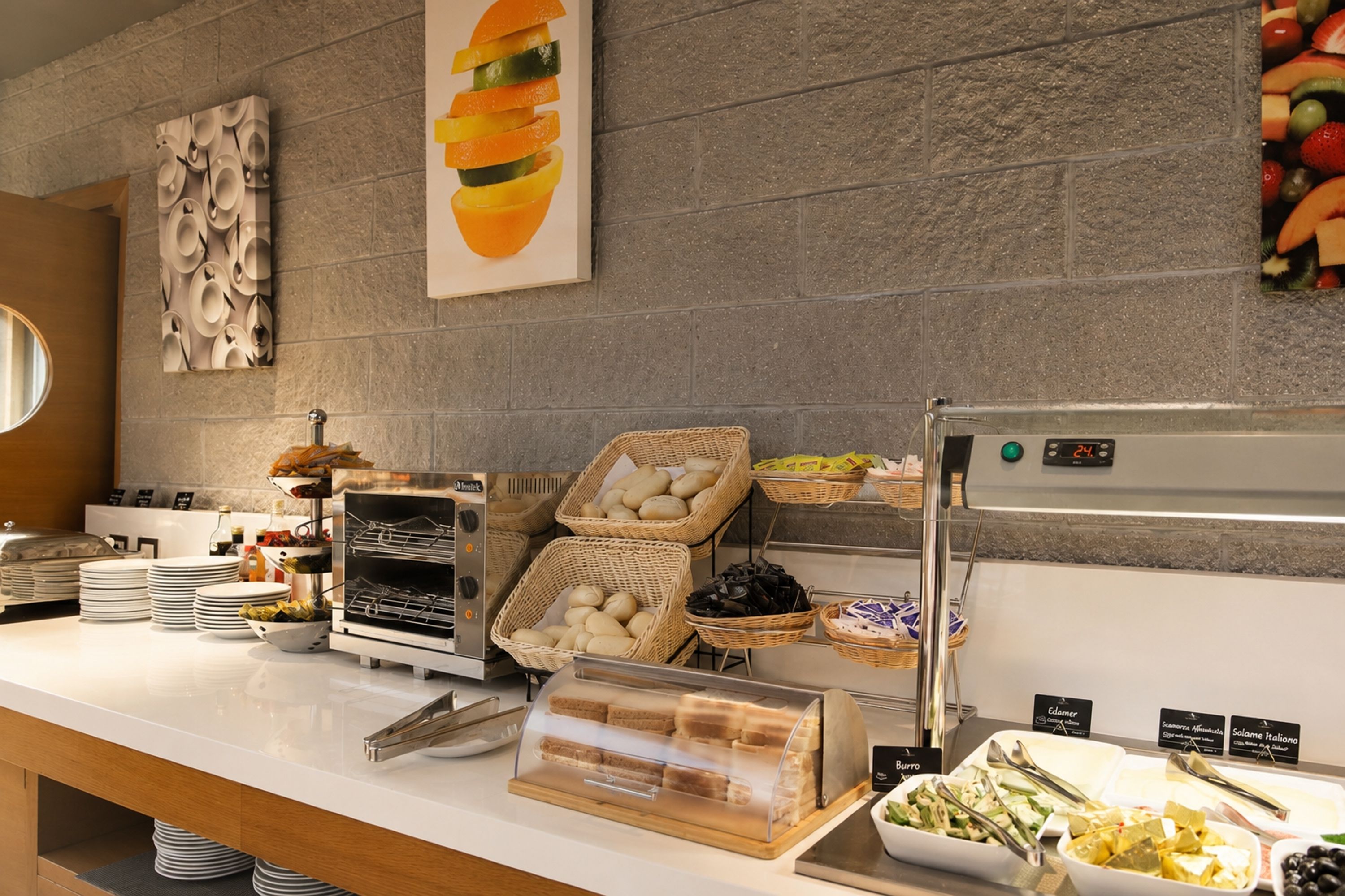 Montaje de bufé con diferentes alimentos, una presentación de panes y un refrigerador.