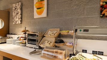 Montaje de bufé con diferentes alimentos, una presentación de panes y un refrigerador.