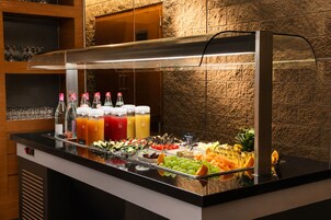 Un bufé con una amplia variedad de comida y bebidas, que incluye frutas, verduras y jugos.
