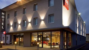 Un hôtel doté d’une façade moderne, de nombreuses fenêtres et d’une entrée bien visible avec un espace détente.