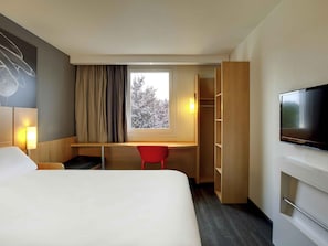 A hotel room with a bed, a desk, a TV, and a wardrobe. - ibis Clermont Ferrand Nord Riom (Riom)