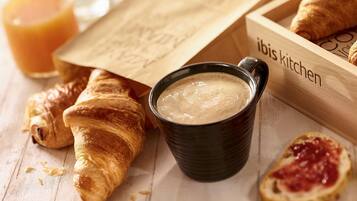 A wooden tray with croissants, a bowl of soup, and a glass of orange juice.