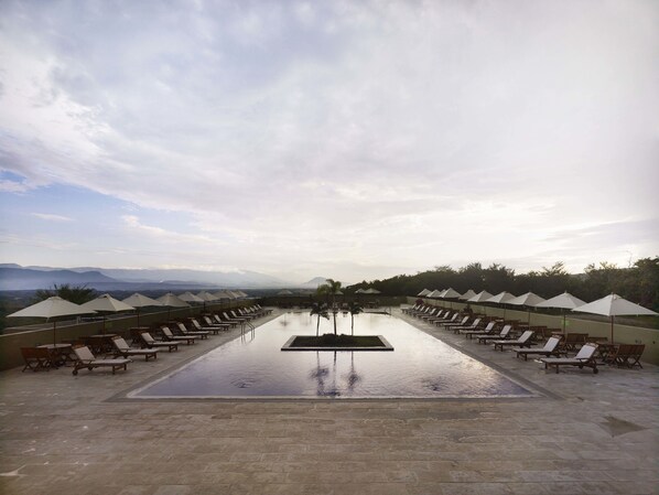Una piscina al aire libre, sombrillas, sillones reclinables de piscina