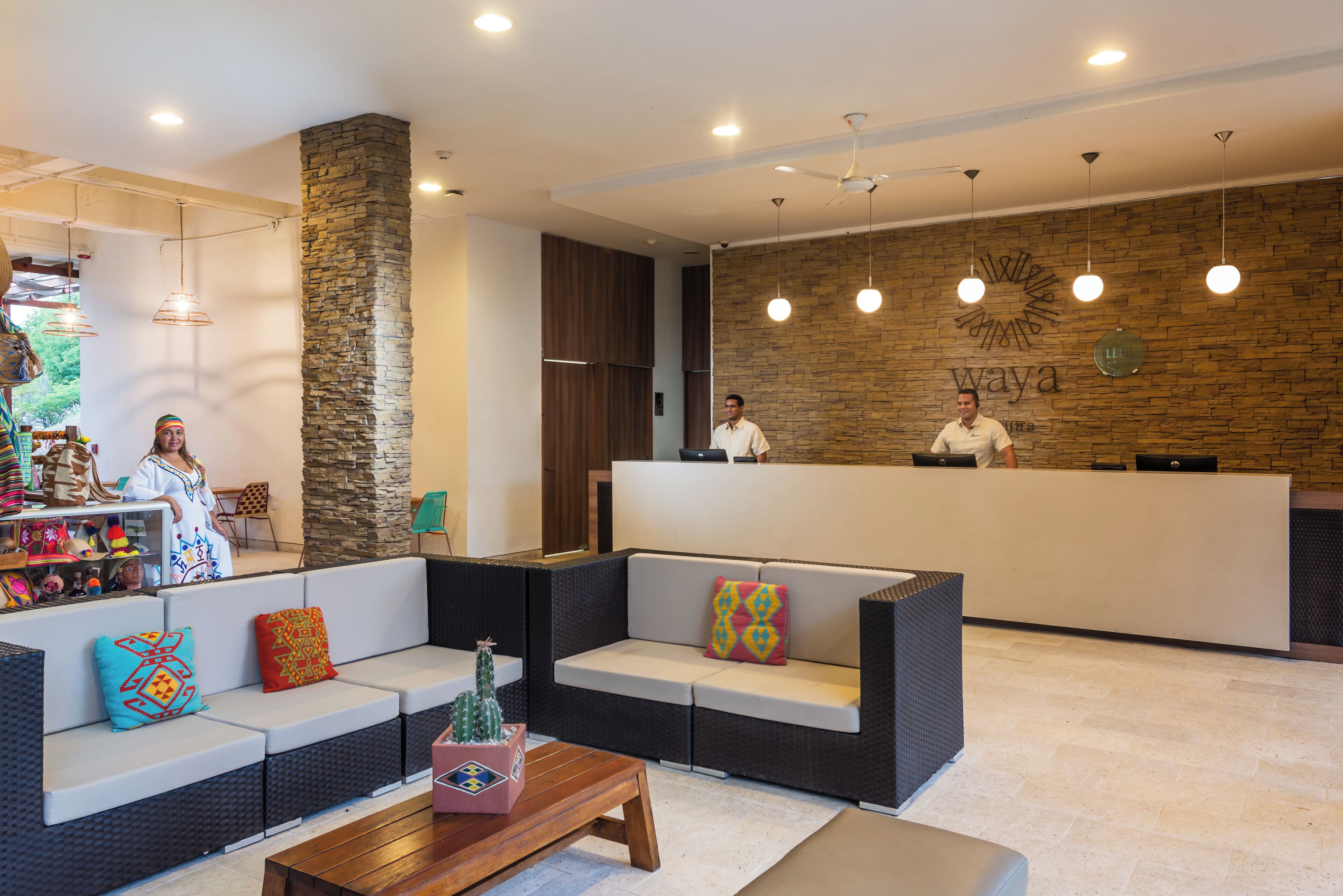 A reception area with a stone wall, a reception desk, and a seating area with cushions and a small table.