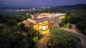 A multi-story building with a rooftop terrace, surrounded by dense vegetation. - Hotel Waya Guajira By OxoHotel (Albania)