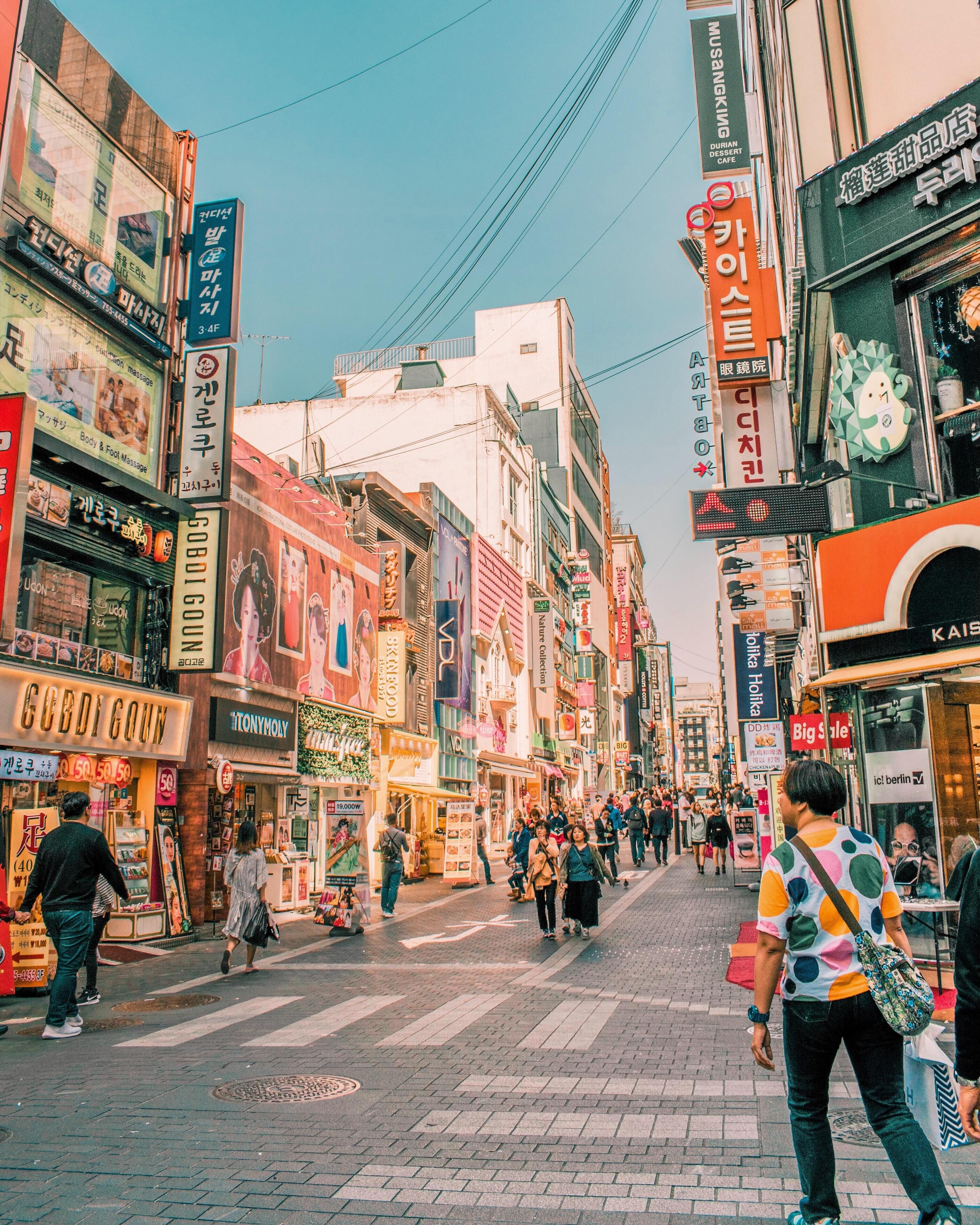 A busy urban street with various shops and signs, including a visible 'GOBI GOWN' store.
