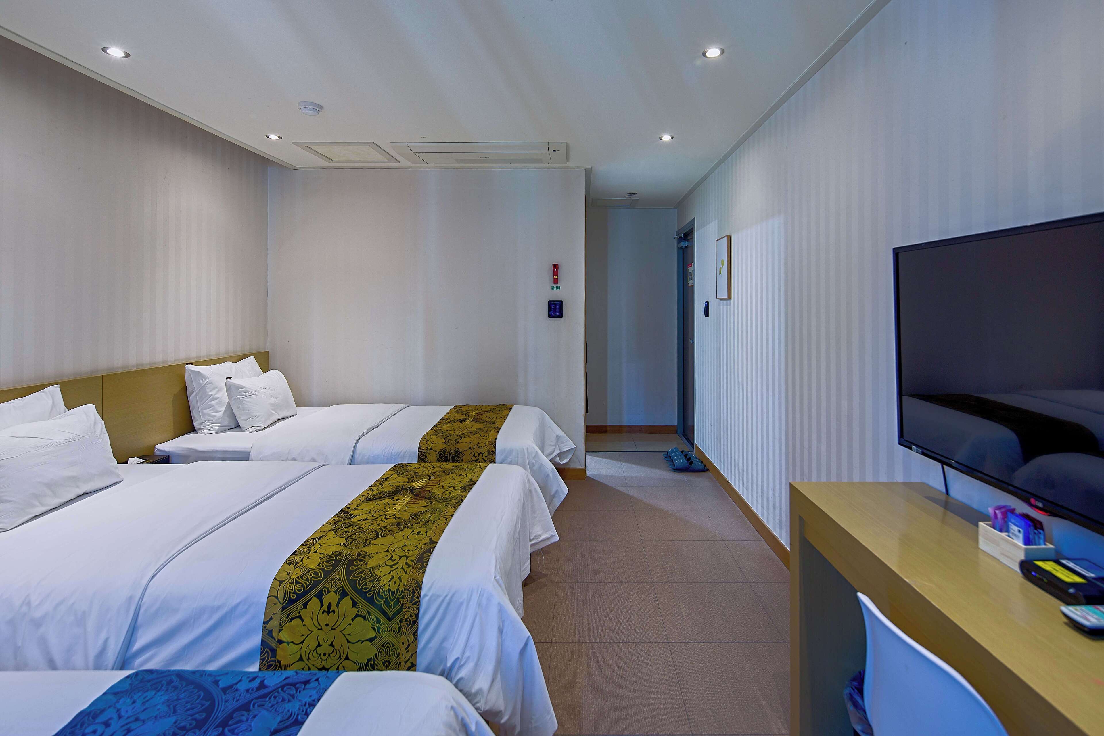 Ein Hotelzimmer mit zwei Betten, einem Fernseher und einem Schreibtisch.