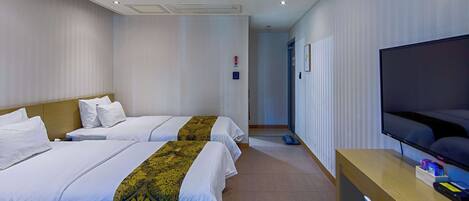 A hotel room with two beds, a TV, and a desk.
