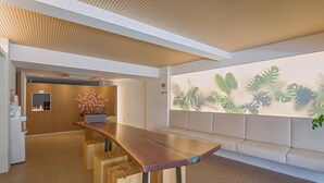 A modern reception area with a wooden reception desk, a seating area with a sofa, and a wall with a tropical leaf mural. - Namsan Hill Hotel (Seoul)