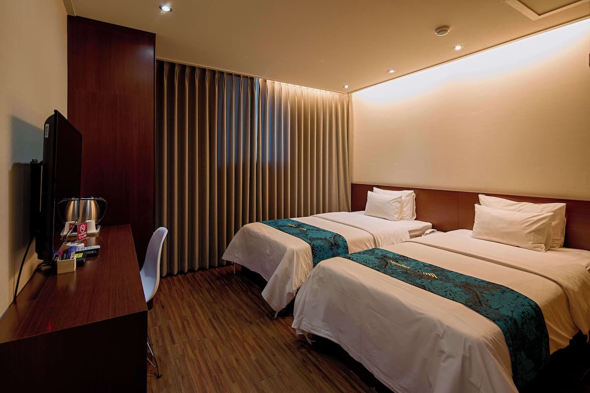 Una habitación de hotel con dos camas, un escritorio, una silla y un televisor.