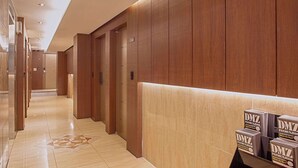 A hotel corridor with wooden paneling, a tiled floor, and a reception desk with DMZ branded boxes. - Namsan Hill Hotel (Seoul)