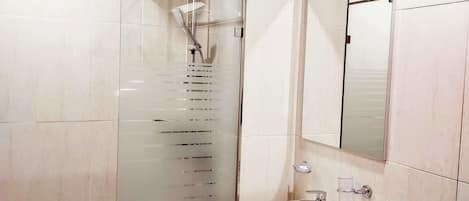 A modern bathroom with a glass-enclosed shower, a white sink, and a toilet.