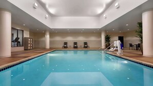 An indoor swimming pool with clear water, surrounded by lounge chairs and a seating area.