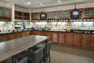 Une cuisine moderne avec des meubles en bois, un îlot central en acier inoxydable et un bar pour prendre le petit-déjeuner.