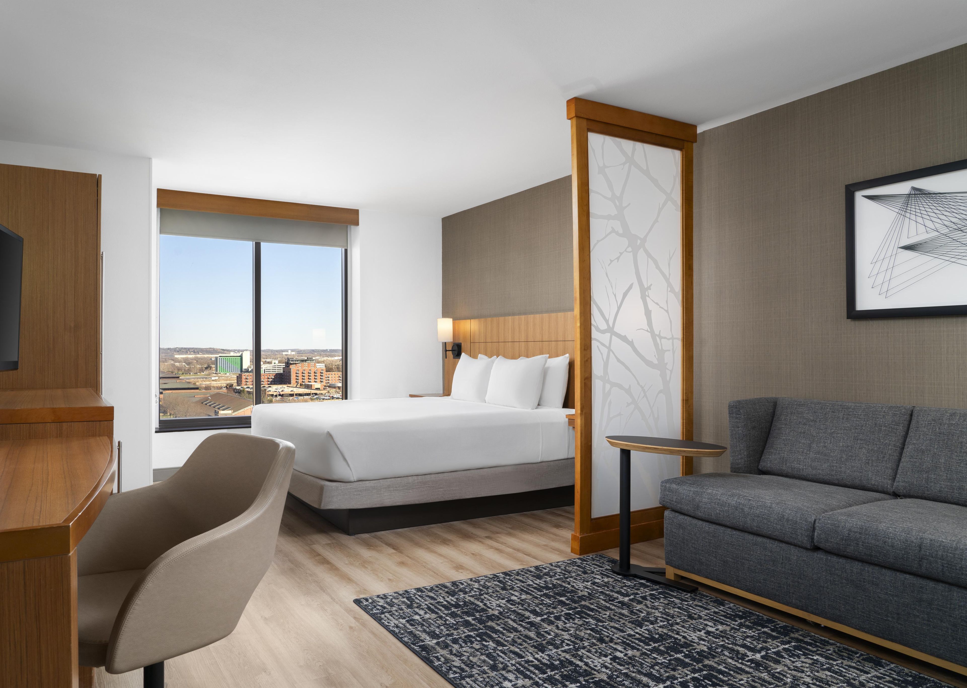 A hotel room with a bed, a sofa, a desk, and a chair.
