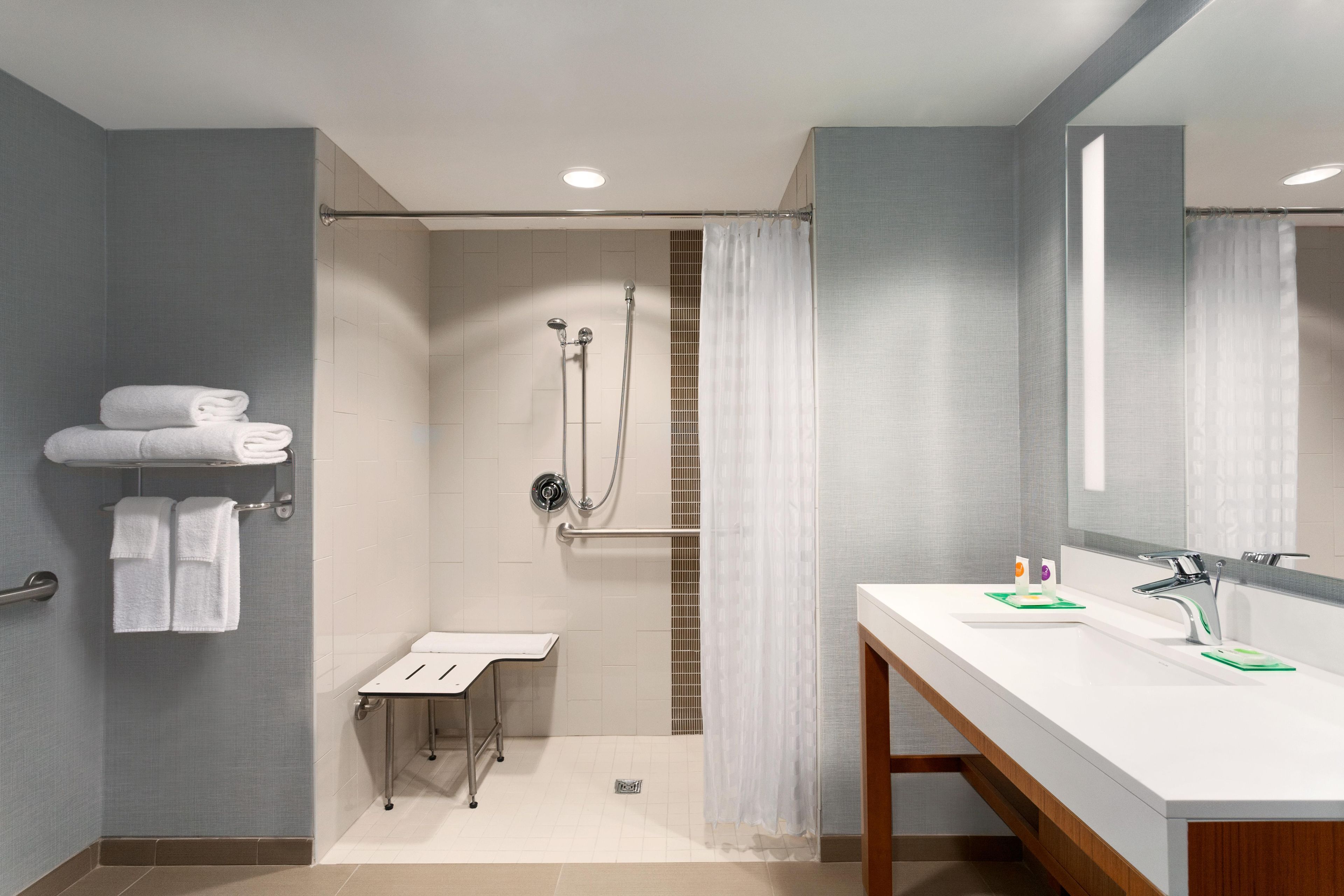 Un baño moderno con ducha, lavamanos y espejo.