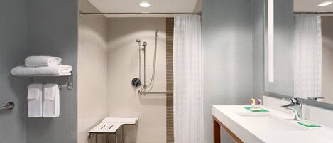Un baño moderno con ducha, lavamanos y espejo.