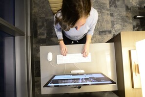Una persona sentada en un escritorio con un teclado y un monitor que muestra una página web.