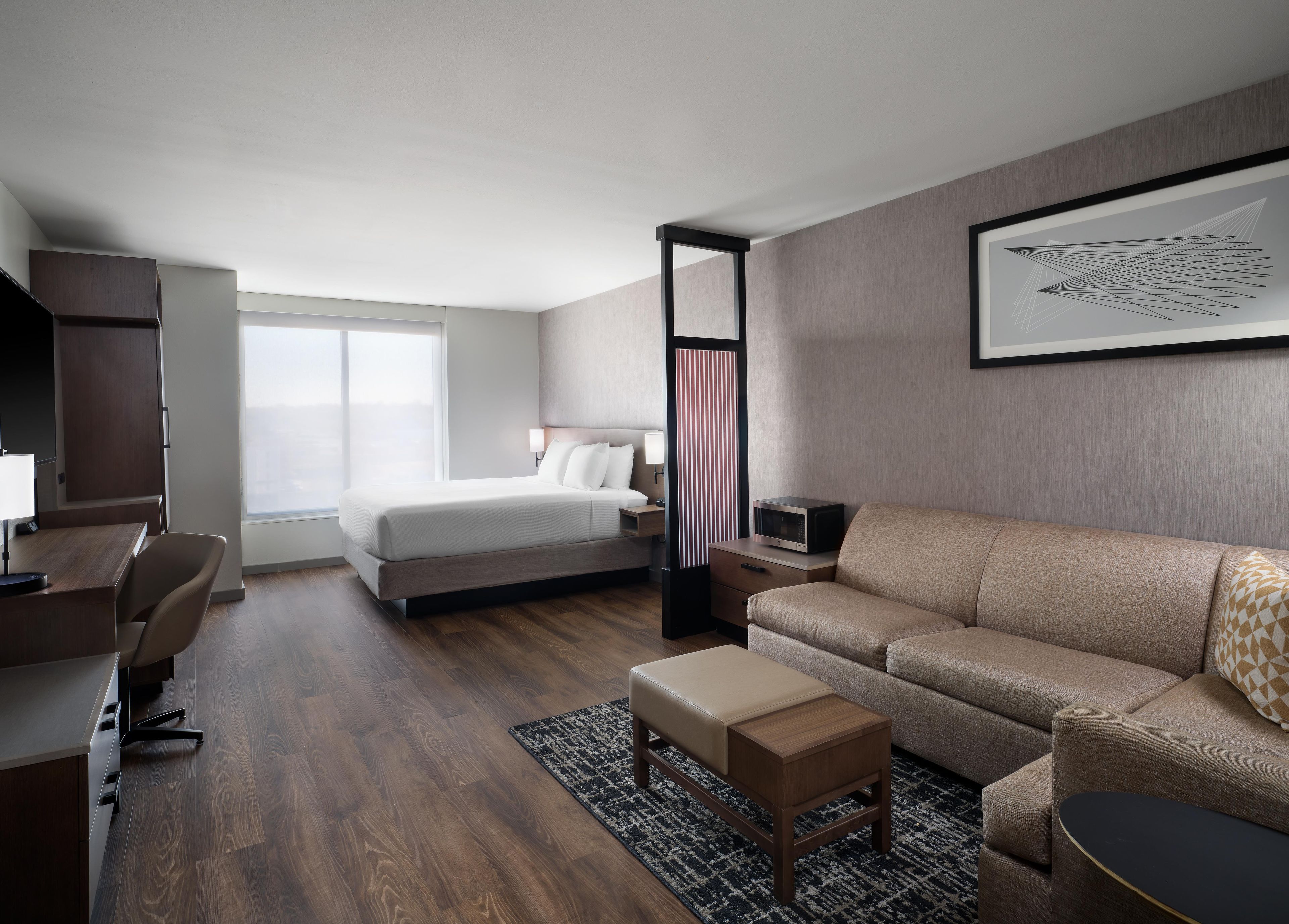 Una habitación de hotel con cama, sofá, escritorio y televisor.