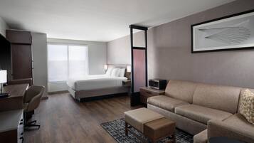 Una habitación de hotel con cama, sofá, escritorio y televisor.