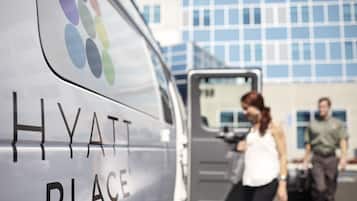 A white van with "HYATT PLACE" written on it, parked in front of a building with a blue and white facade.