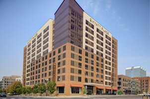 A multi-story hotel with a prominent "Hyatt Place" sign, featuring a modern architectural design with a mix of brick and glass facades.