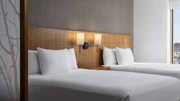 A hotel room with two beds, a wooden headboard, and a city view.